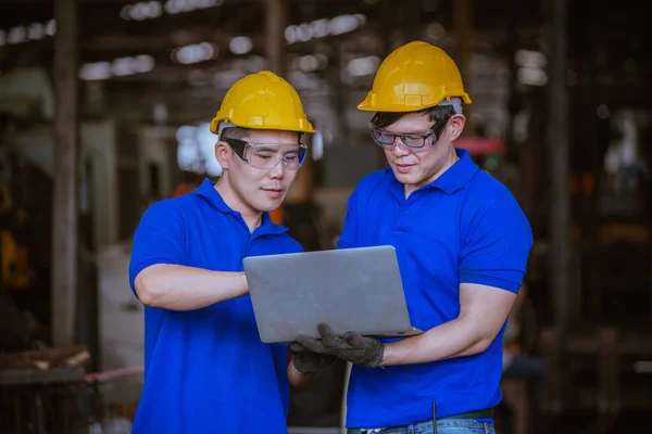 Industry worker under inspection and checking production process on factory station by laptop,Engineer wearing casual uniform and safety helmet in work