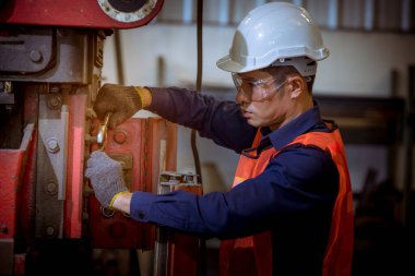 Cam ve güvenlik üniforması giyen endüstri mühendisleri, endüstri fabrikasında çalışan nesne kontrol mekanizmasını ölçmek için Vernier Caliper kullandılar..