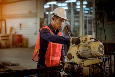 Cam ve güvenlik üniforması giyen endüstri mühendisleri, endüstri fabrikasında çalışan nesne kontrol mekanizmasını ölçmek için Vernier Caliper kullandılar..
