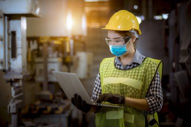 Fabrikadaki kirliliği ve virüsü korumak için güvenlik maskesi takarak fabrika istasyonunda kontrol altında tutulan bir portre mühendisi..