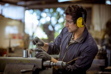 Cam, kulaklık ve güvenlik üniforması giyen endüstri mühendisleri, endüstri fabrikasında çalışan nesne kontrol makinesini ölçmek için Vernier Caliper kullandılar..