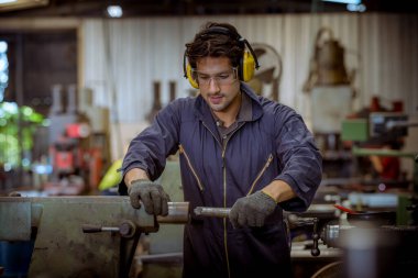 Cam, kulaklık ve güvenlik üniforması giyen endüstri mühendisleri, endüstri fabrikasında çalışan nesne kontrol makinesini ölçmek için Vernier Caliper kullandılar..