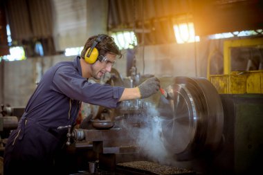 Güvenlik üniforması giyen endüstri işçisi endüstriyel fabrikada çalışan yağ kontrol makinesini kullanıyordu..