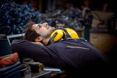 Üniformalı ve kulaklıklı bir portre işçisi işten sonra ofisinde dinleniyor..