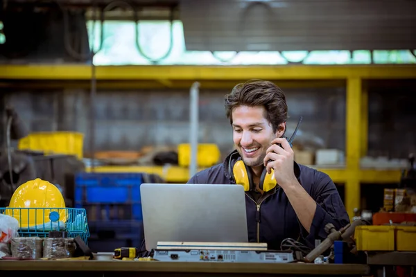 A Industry worker wearing safety uniform ,ear phone used radio communication with laptop for common and discussion work in factory industry.