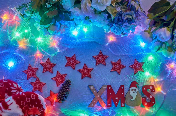 Red Christmas wooden stars with the inscription and red warm soft slippers With included garlands on a light background. — Stock Photo, Image