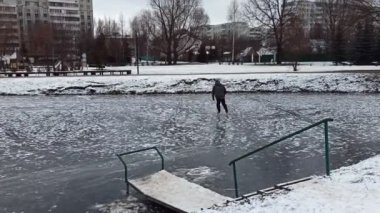 45 yaşında bir adam parktaki donmuş bir gölde paten kayıyor..