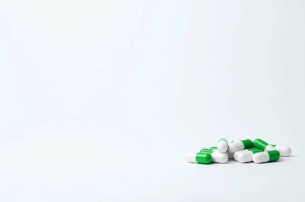 Açık arkaplanlı yeşil ve beyaz haplar. Mesaj için yer var. Biyolojik takviyeler, vitaminler, sağlık ilaçları.