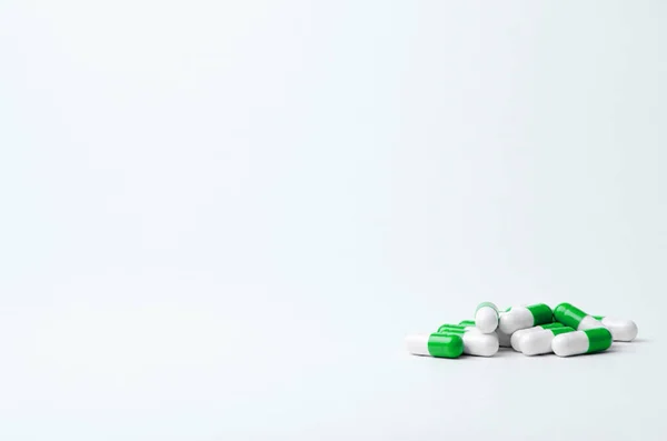 Grüne und weiße Pillen auf hellem Hintergrund mit Platz für Text. Biologische Nahrungsergänzungsmittel, Vitamine, Medikamente für die Gesundheit. Stockbild