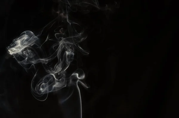 Abstract puffs of smoke on the left side of the frame on a dark background with a place for text, mysticism, fantasy — 스톡 사진