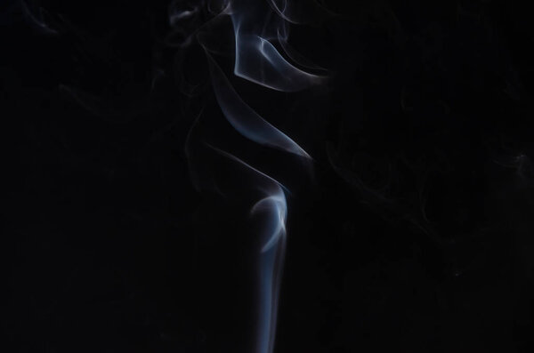Abstract puffs of smoke on the left side of the frame on a dark background with a place for text, mysticism, fantasy,magic
