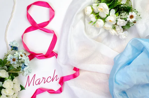 Uluslararası Kadınlar Günü, 8 Mart. 8 numara, havadar saten kumaş arka plandaki kırmızı saten kurdeleden. Çiçek buketi ve pembe incilerle. Üstünde 8 Mart yazılıydı.