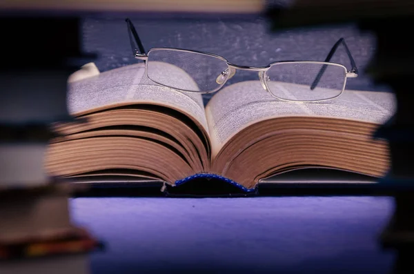 Big book on the table through a stack of books with a place for text, writer day, poet, library.