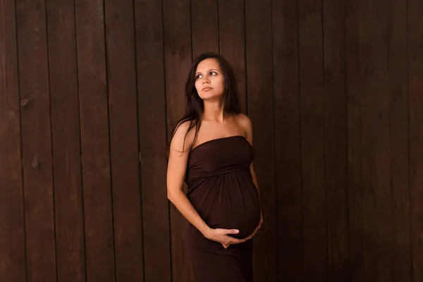 Pregnant Woman Red Dress Holds Hands Belly Dark Brown Background — Stock Photo, Image