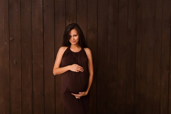 Pregnant Woman Red Dress Holds Hands Belly Dark Brown Background — Stock Photo, Image