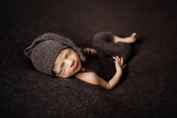 Cute newborn baby on a brown blanket. Sleeping baby on a dark background. Closeup portrait of newborn baby. Baby goods packing template. Nursery. Medical and healthy concept.