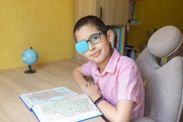 本で宿題を勉強するパッチ付き眼鏡の少年 隔離だ 距離学習 遠隔教育 怠惰な目 近視症 痙攣を治療する — ストック写真