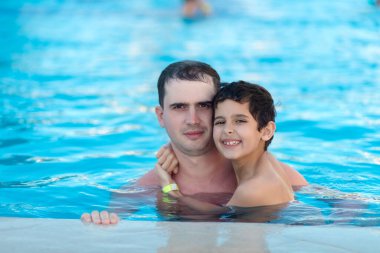 Erkek ve çocuk yüzme havuzundalar.