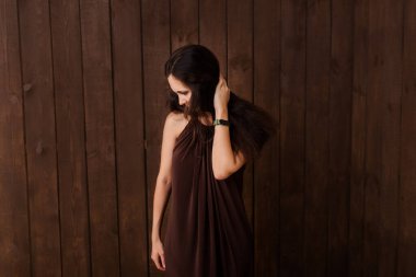 Koyu kahverengi arka planda kahverengi elbiseli bir kadın. Hamilelik, annelik, beklenti konsepti. Güzel duygusal fotoğraf. 