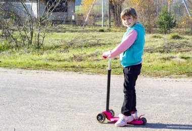 Küçük kız kaykaya biniyor.