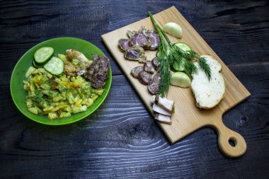 Sebzeli kızarmış patates, bir kase patates ve domuz pastırması ve sosisli ahşap tahta.