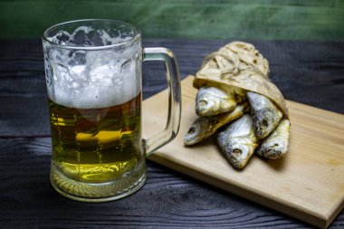 Bira ve kurutulmuş balık, koyu bir arka planda.