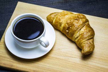 Kahve fincanın yanında kruvasan, üst manzara.