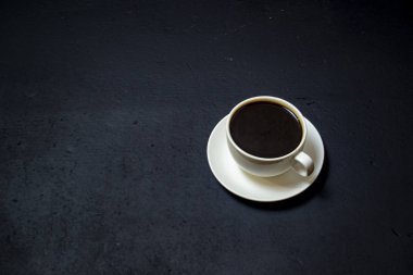 Siyah arka planda beyaz bardakta kahve.