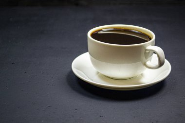 Siyah arka planda beyaz bardakta kahve.