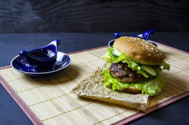 Salatalıklı hamburger ve servis tabağında çay ile yeşillik.