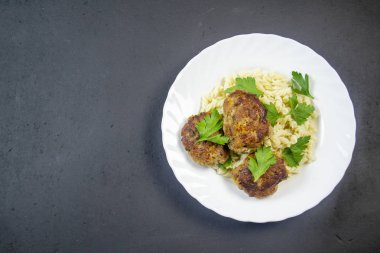 Tahtadaki beyaz tabakta köfteli makarna.