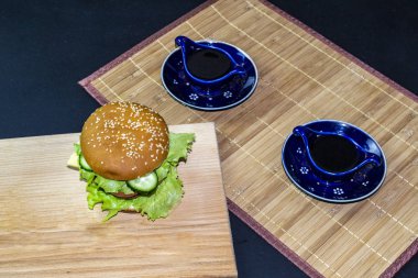 Koyu bir arka planda tahta tepside hamburger.