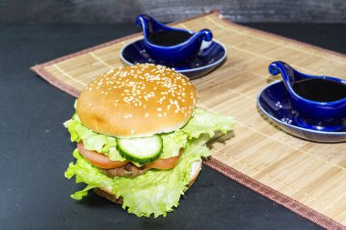 Koyu bir arka planda tahta tepside hamburger.