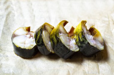 Tütsülenmiş uskumru balığı parçalara ayrılır ve kağıt peçetenin üzerinde yatar.