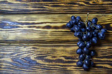 Tahta bir masada siyah üzüm dalı, üst manzara.