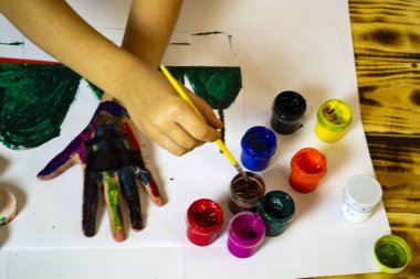 young girl draws on hands at a table, selective focus