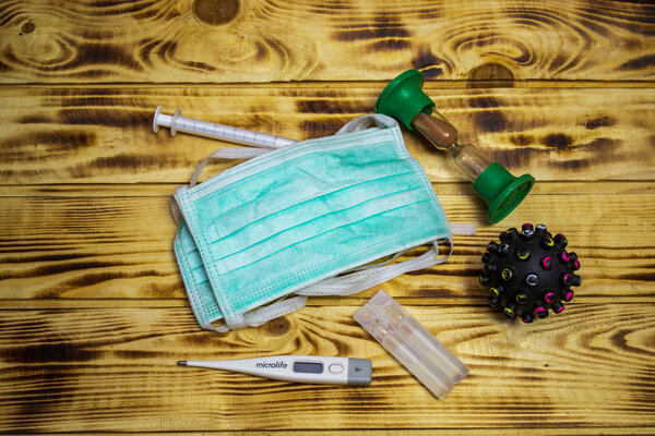 Coronavirus quarantine concept, on a wooden background, medical mask with capsule and virus