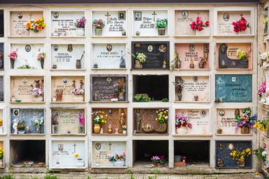 PETRELLA SALTO, İtalya. 15 Nisan 2018: İtalya 'nın Rieti ilindeki Petrella Salto belediyesine bağlı Hıristiyan din mezarlığı. İçinde tabut olan bir sürü oda olan duvar. Çiçekler ve mumlar..