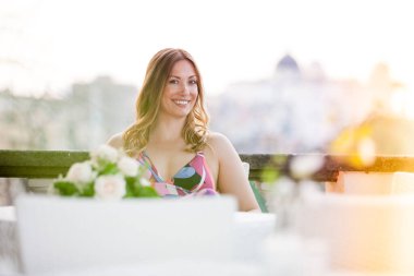 Dışarıda oturan güzel ve büyüleyici gülümseyen kadın. Olumlu ve neşeli bir tavırla bakıyorum. Bulanık arkaplan.