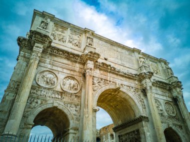 Konstantin Kemeri (İtalyanca: Arco di Costantino). Roma 'daki Zafer Kemeri, Colosseum ve Palatine Tepesi arasında yer alıyor. Arka planda bulutlar olan mavi gökyüzü.