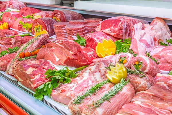 Bir alışveriş merkezinde kasaplık yapan et bölümü. Düzenli ve yaratıcı bir şekilde gösterilen çeşitli et türleri. Yiyecek süpermarketinin rafları. Süsleme ve süsleme için portakal ve sebze.