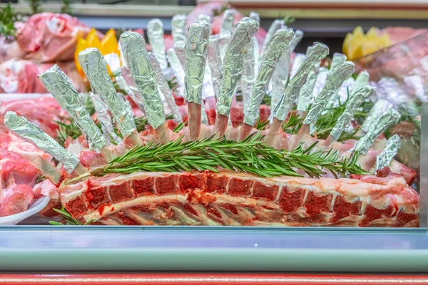 Meat department in butchery inside a mall. Various types of meat displayed in an orderly and creative way. Shelves of a food supermarket. Orange and vegetables for decoration and topping.