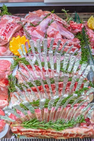 Meat department in butchery inside a mall. Various types of meat displayed in an orderly and creative way. Shelves of a food supermarket. Orange and vegetables for decoration and topping.