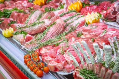 Bir alışveriş merkezinde kasaplık yapan et bölümü. Düzenli ve yaratıcı bir şekilde gösterilen çeşitli et türleri. Yiyecek süpermarketinin rafları. Süsleme ve süsleme için portakal ve sebze.