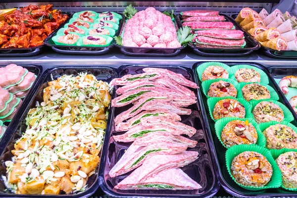 Butcher, meat department. Several products displayed in a showcase. Italian food in tray with different preparation and meat ingredients.