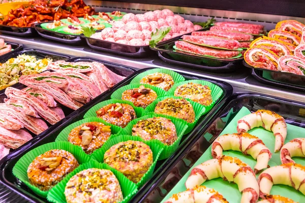 Meat department in butchery inside a mall. Various types of meat displayed in an orderly and creative way. Shelves of a food supermarket. Orange and vegetables for decoration and topping.