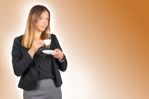 Business woman drinking coffee in cup. Work pause. A standing woman having a coffee during her break. The beautiful young woman is drinking holding a small white cup of coffee.