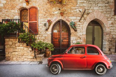 Klasik İtalyan manzarası. Küçük antika kırmızı bir araba. Fiat 500, eski İtalyan evi. Minik, eski bir nostaljik kırmızı arabası var. Fiat 500. Assisi, İtalya.