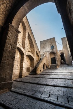Ortaçağ kalesi. Kemer tak ve merdivenleri çık. İtalyan tarihi mimarisi. Napoli, İtalya 'daki eski şatoda yay ve merdivenlerle mücadele eden antik bir bölge. Güzel bir günde mavi gökyüzü. Merkezde hareket bulanıklığı olan turistler sağda.