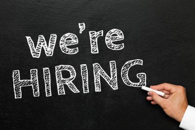 Parmakları arasında tebeşirle yazı yazan bir el işe aldığımız metni karatahtaya yazıyor..